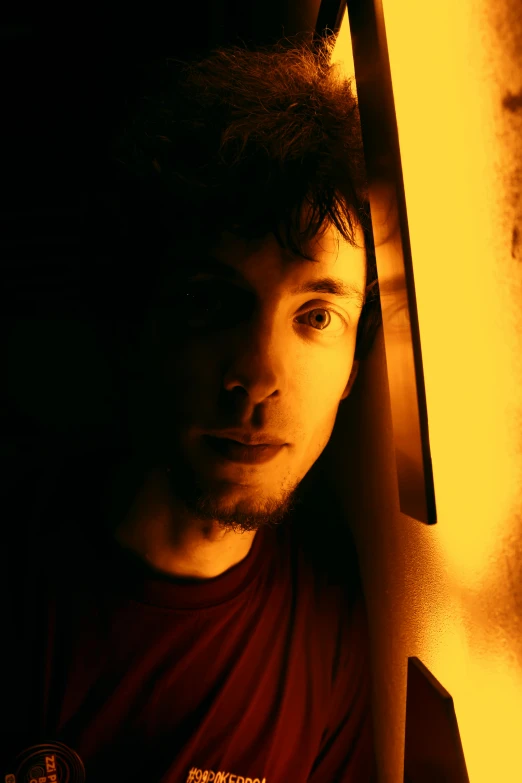 man wearing red shirt in dark room with sunlight coming through
