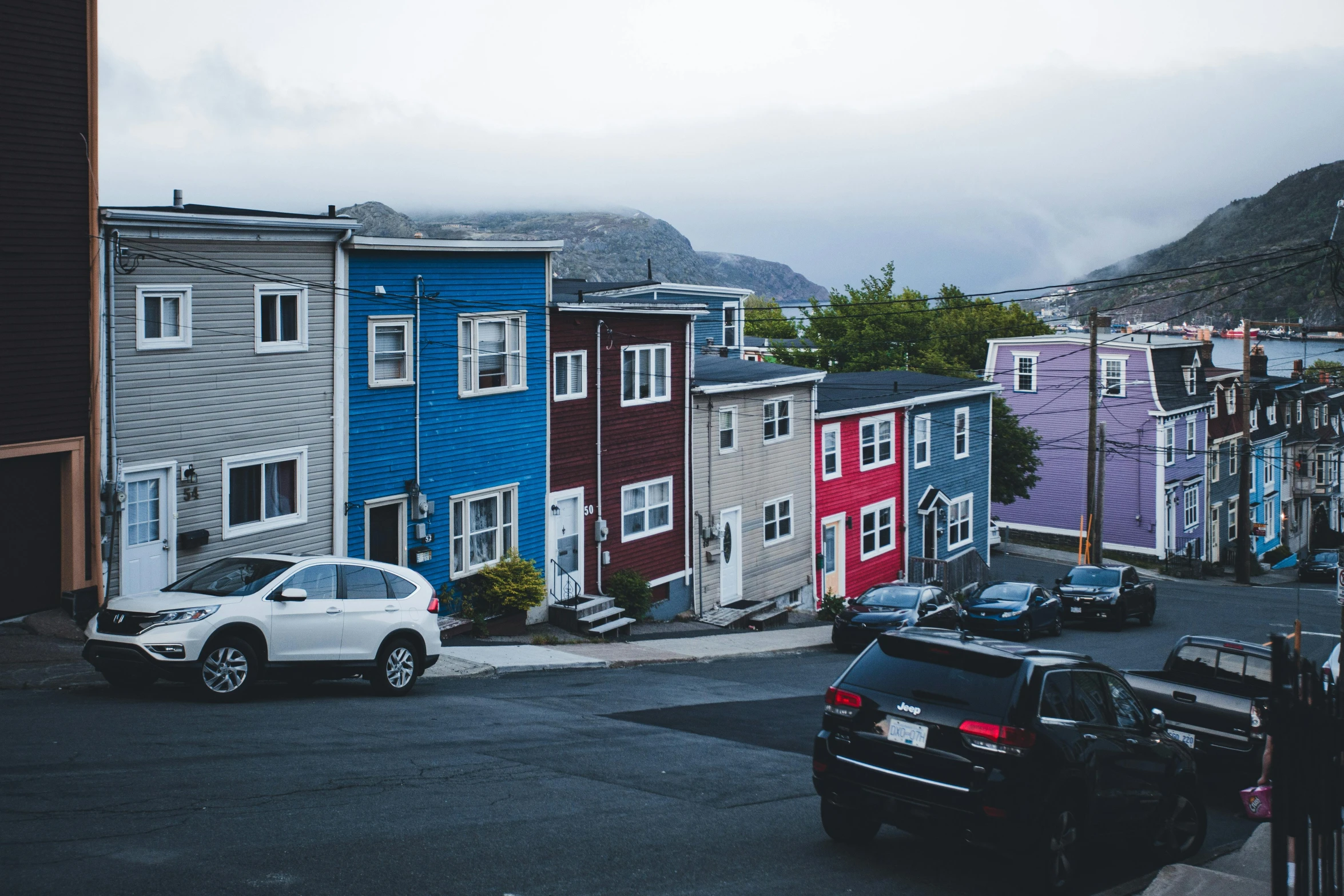 a row of houses on the street with cars parked in the lot