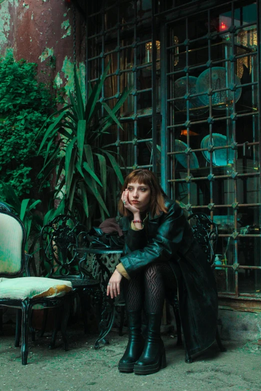 a woman in a black coat sits next to an iron gate