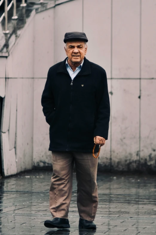 a man standing on a rainy day in an overcoat