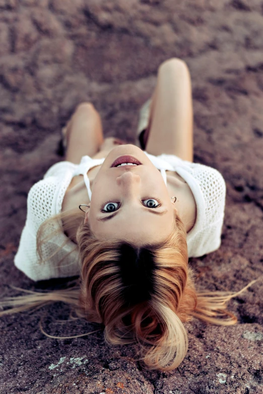 a very attractive lady with long hair laying on the ground