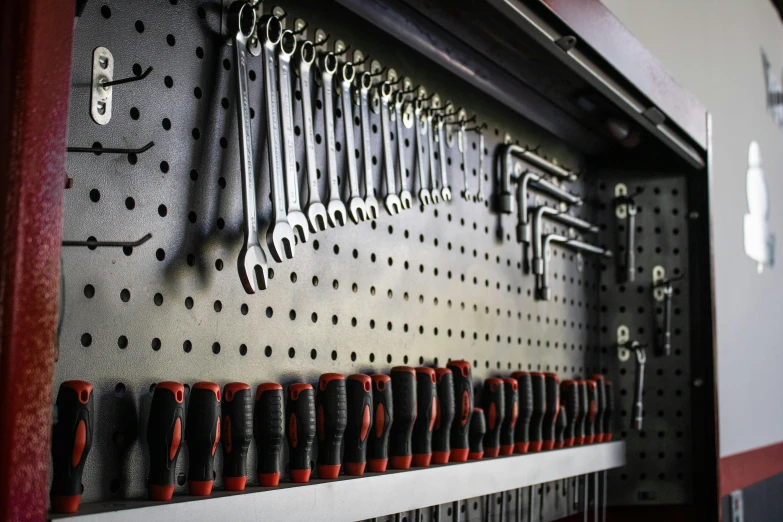 a bunch of wrench hooks and tools are on the wall