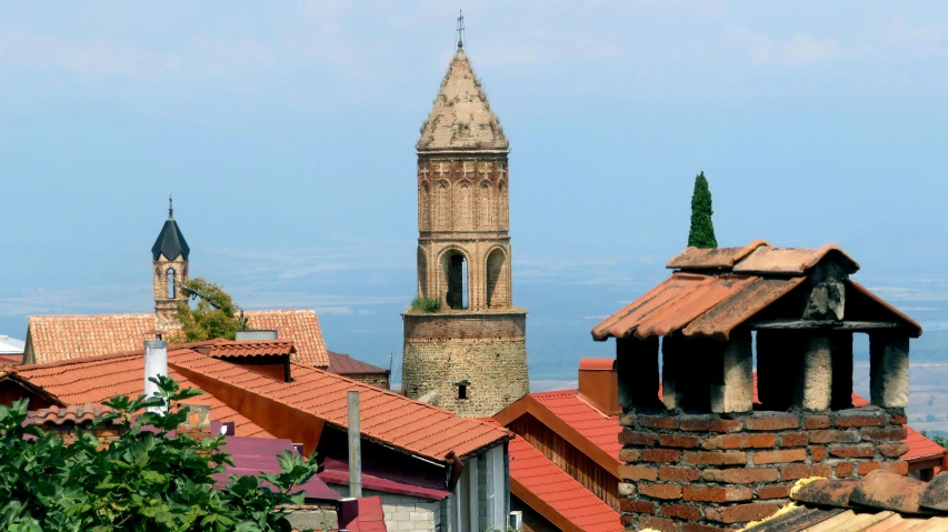 a clock tower seen above a city with red roof tops