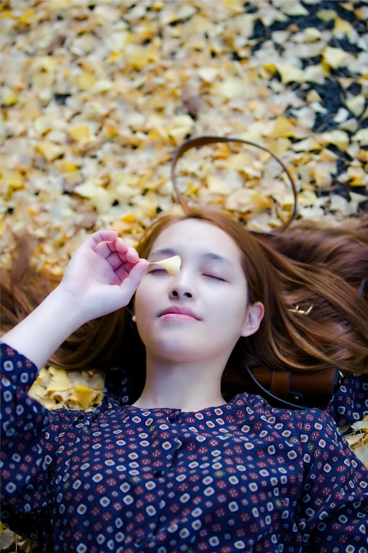 a girl lies on the ground in front of a pile of dried flowers