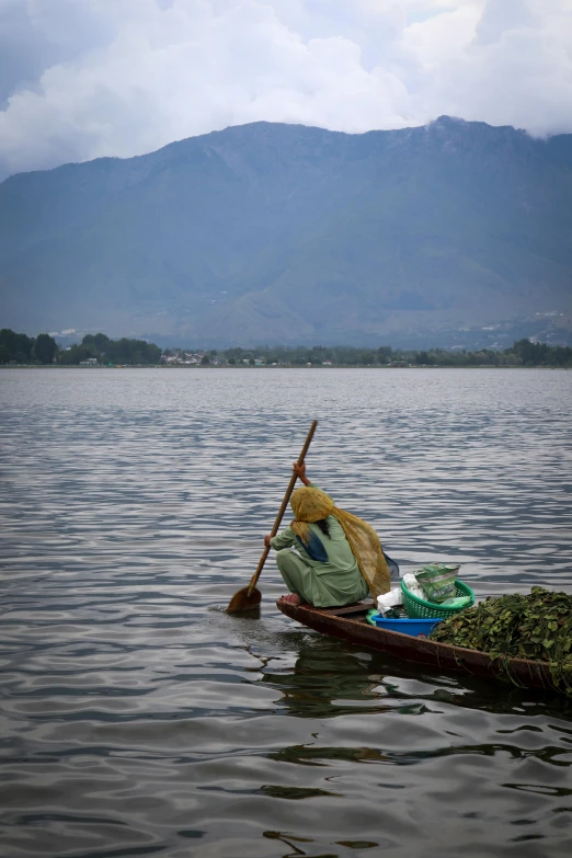 a row boat with a colorful umbrella sits in the middle of the lake