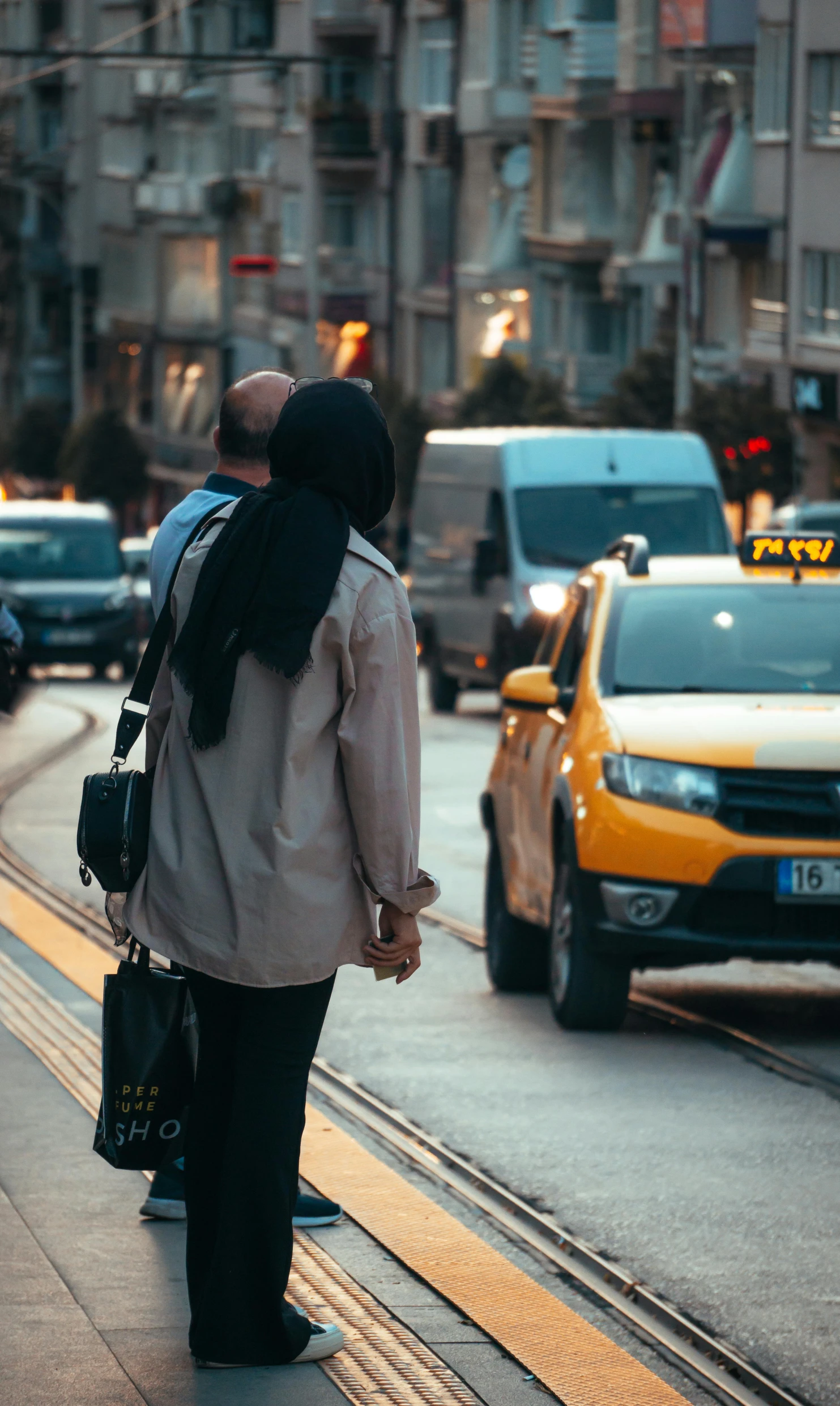 two people walking along side a busy city street