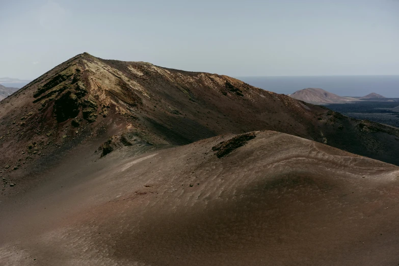 the view from the summit of this large sand dune, shows a small amount of dirt that sits on top