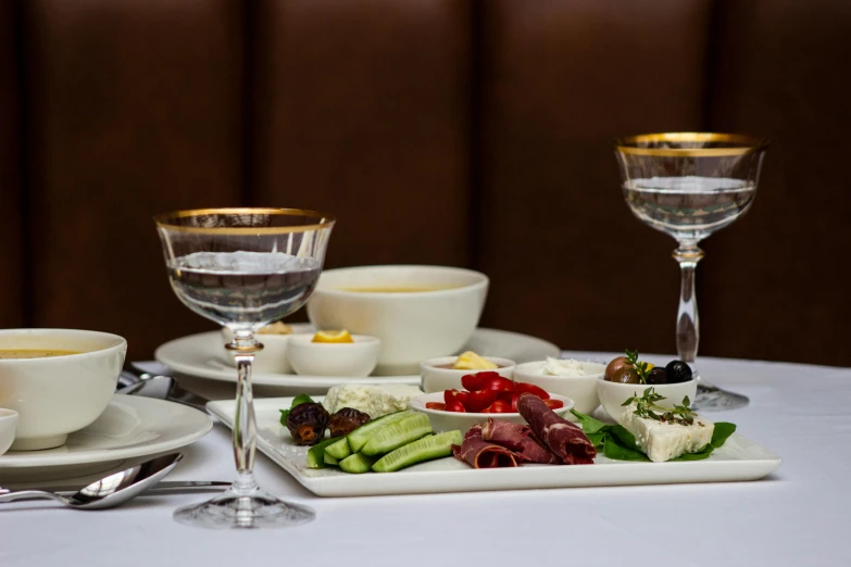 a tray with some food next to glass of wine and two glasses