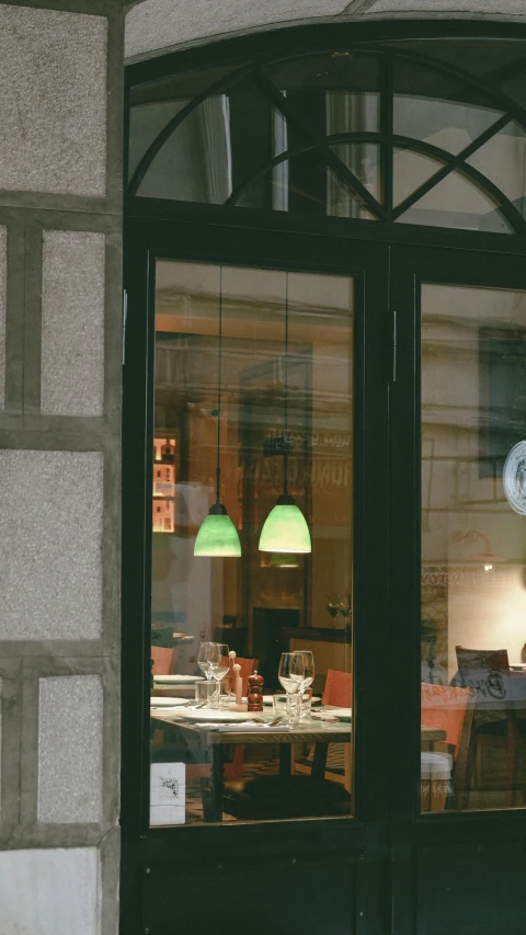 an outside view of a restaurant with a circular glass window that has two lamps