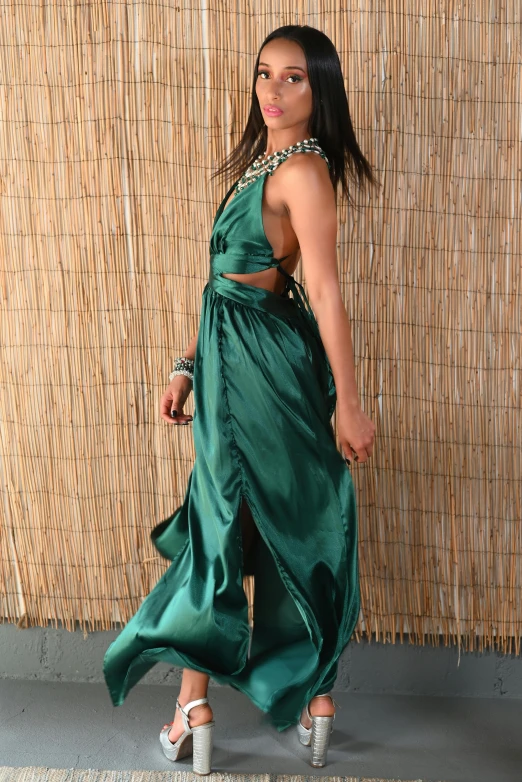 a woman wearing a green dress poses with her handbag