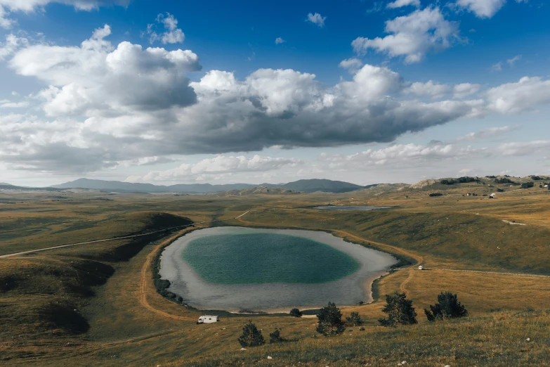 there is a large lake surrounded by a grass field