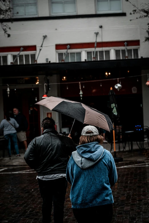 two people with umbrellas standing outside in the rain