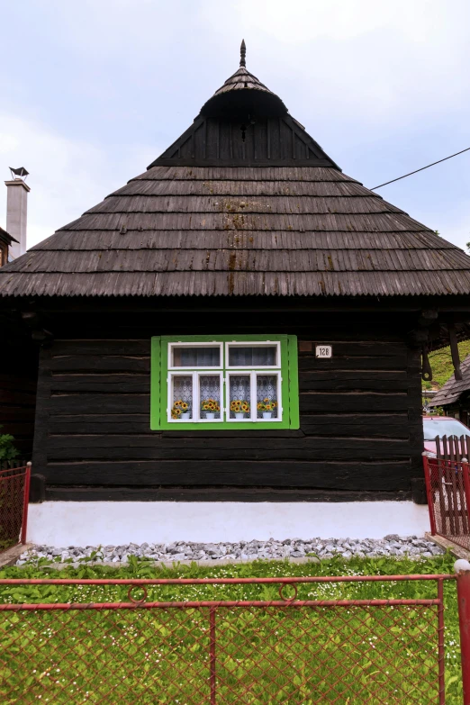 a small wooden cabin with a green window