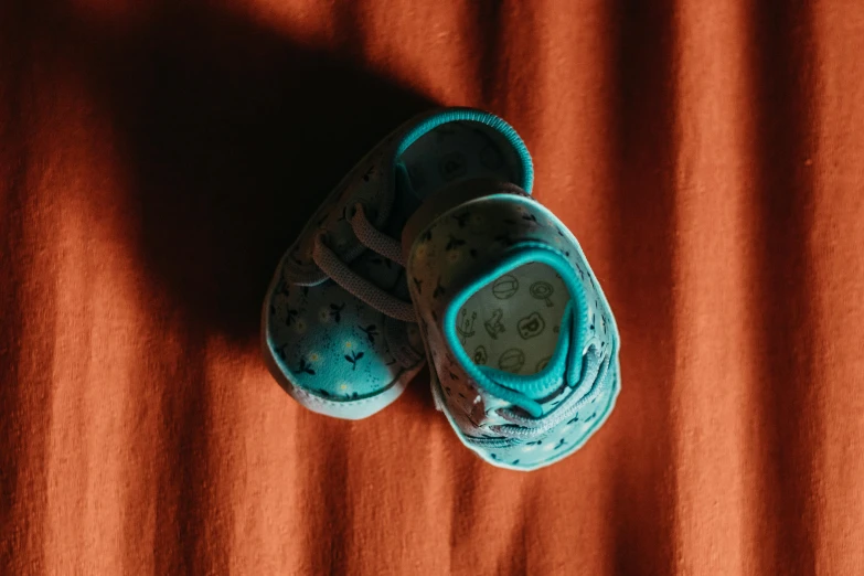 a pair of blue shoes sits atop a red sheet