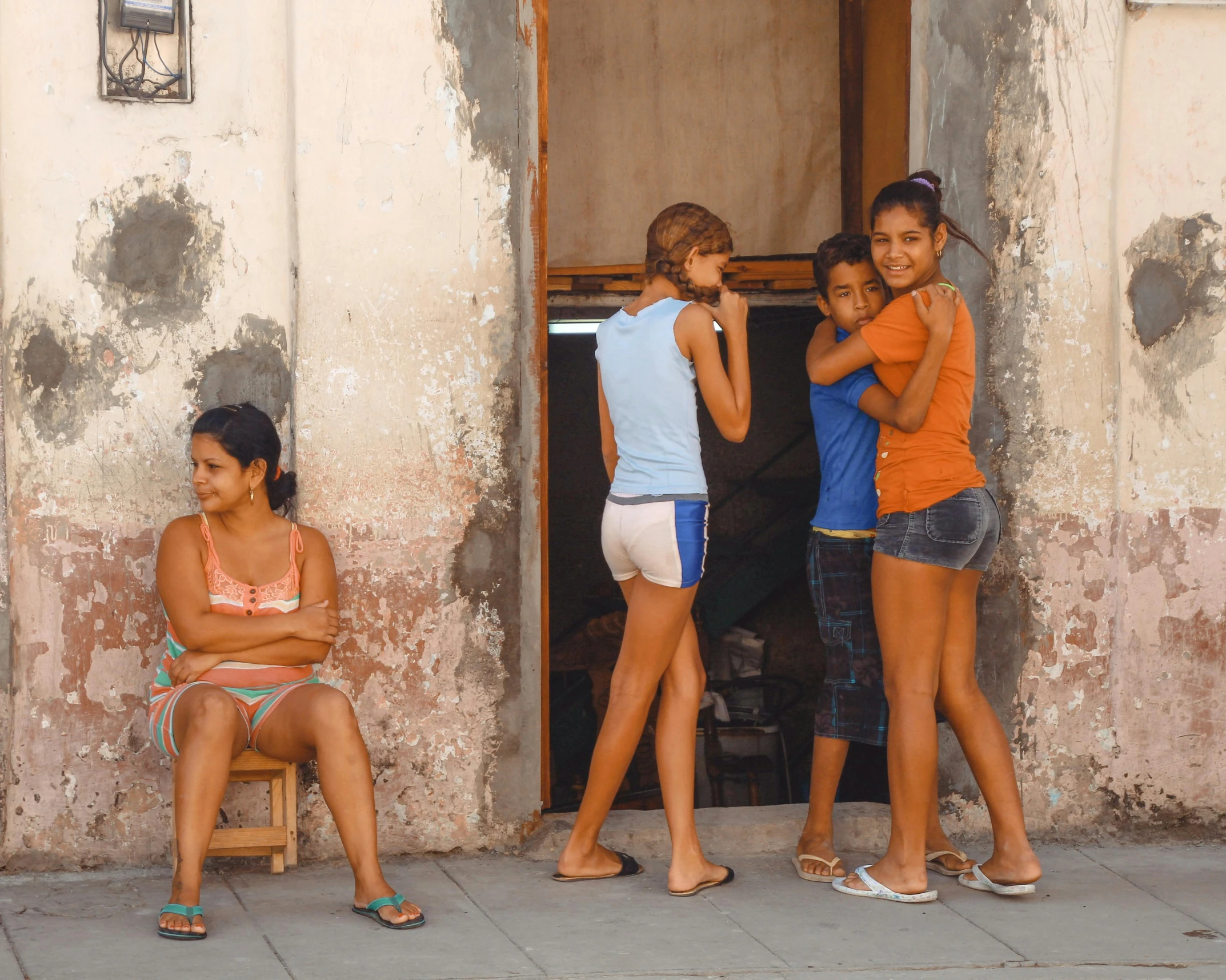 a group of three girls sitting on a bench in front of a building