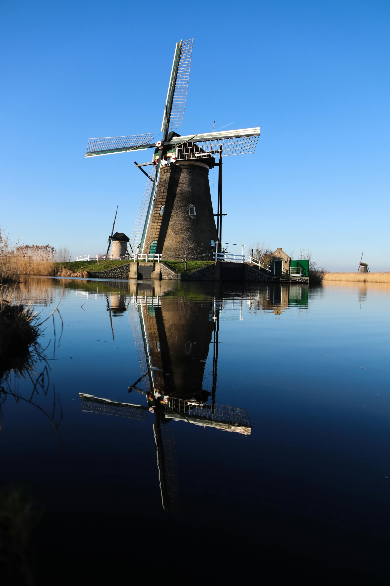 a windmill in water that is next to grass