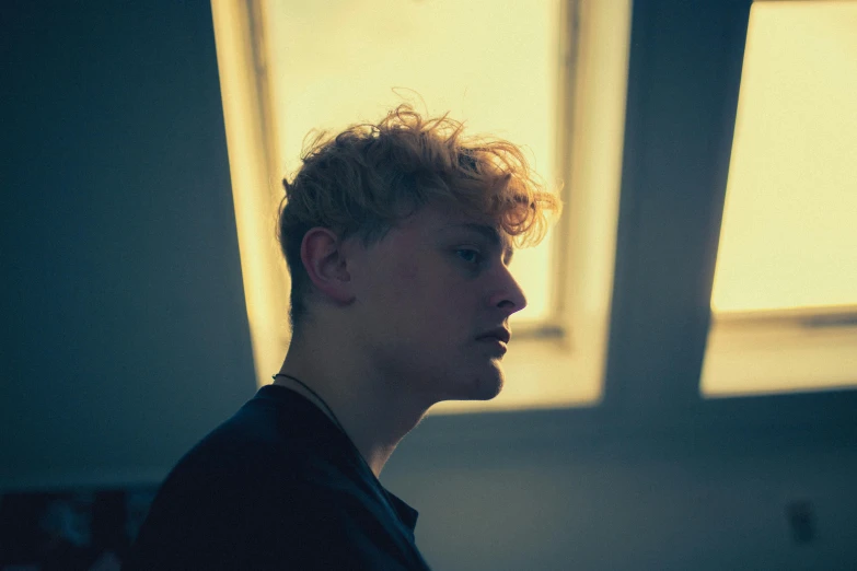 man standing in room next to window and looking off