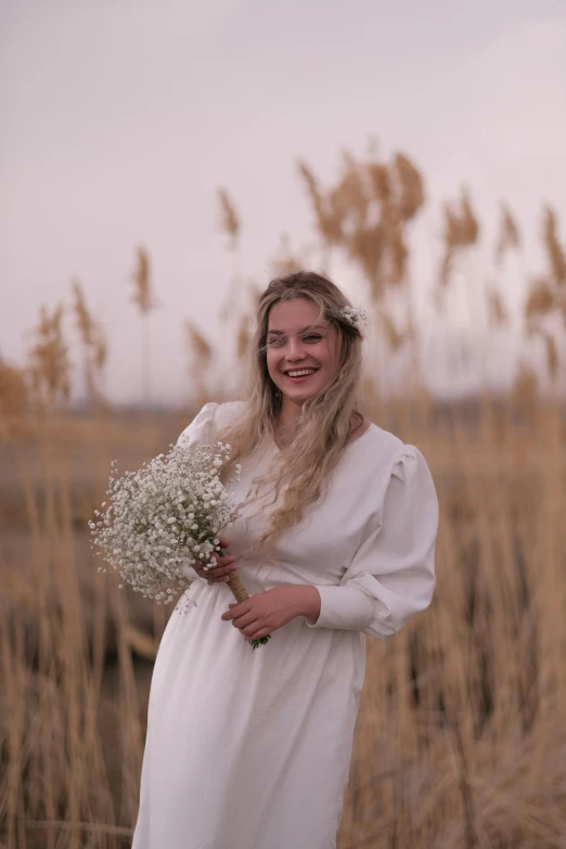 a girl in a white dress holding flowers and posing for a po