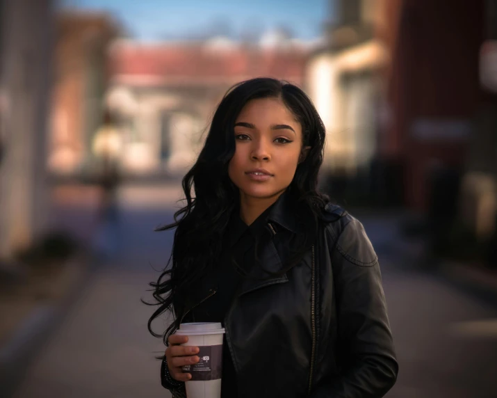 a woman walking down the street holding a coffee cup