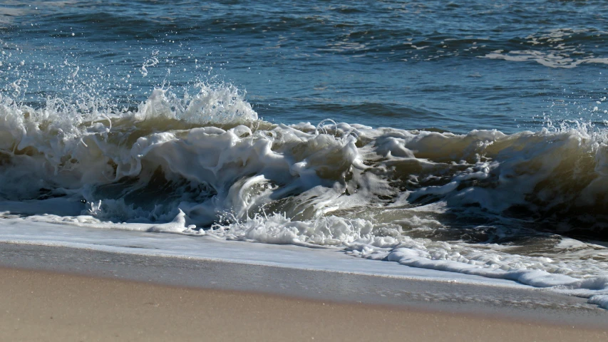 a wave cresting on the sand and water