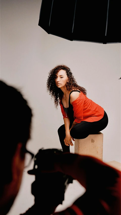 a woman crouches down with one foot on a block, as the camera man squats behind her