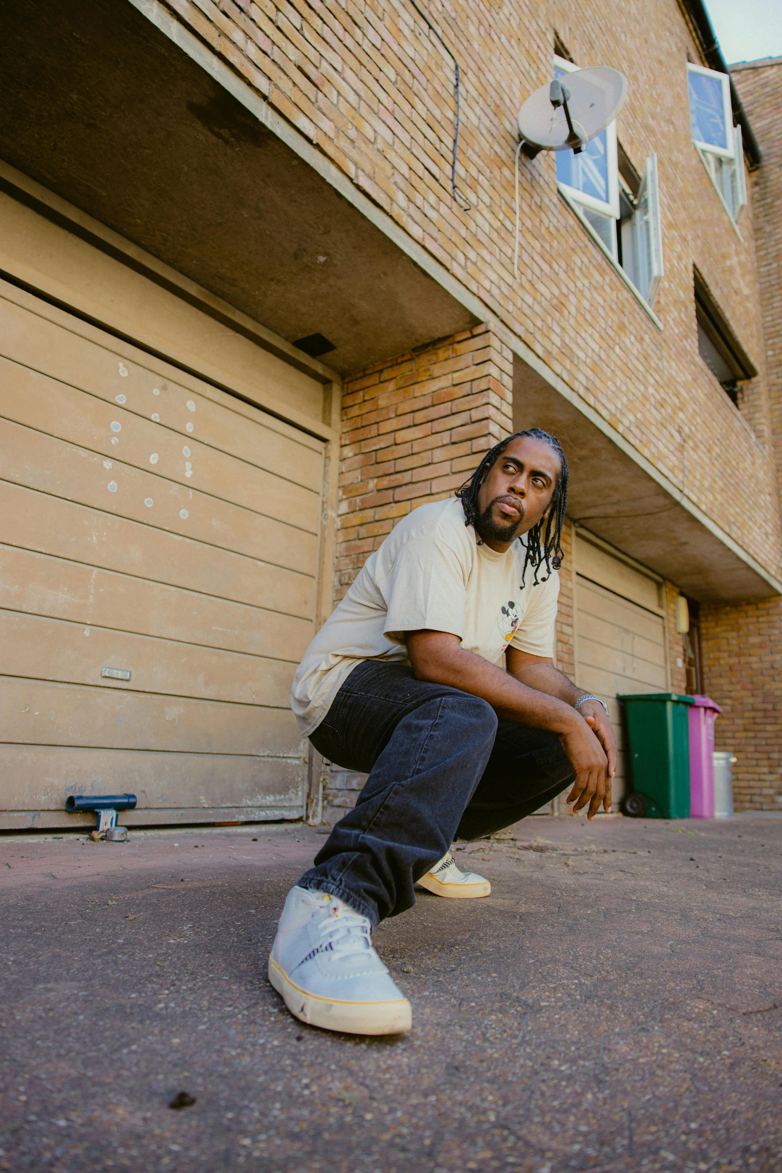 a man kneeling down with his foot on the ground in front of a garage