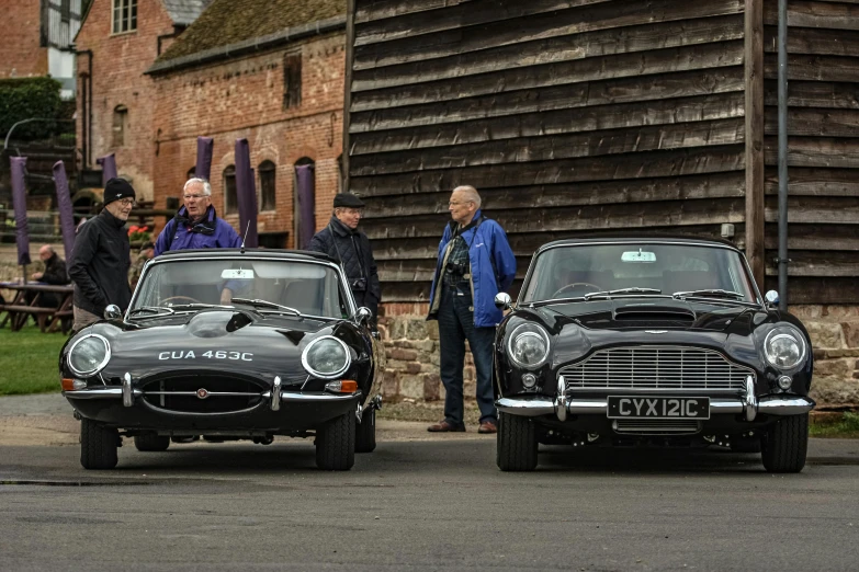 some classic cars parked near an older brick building