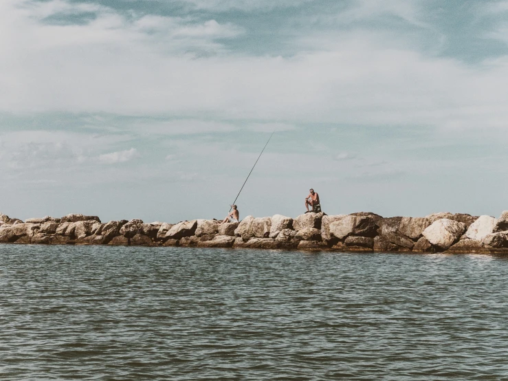 a man in the water is fishing on rocks