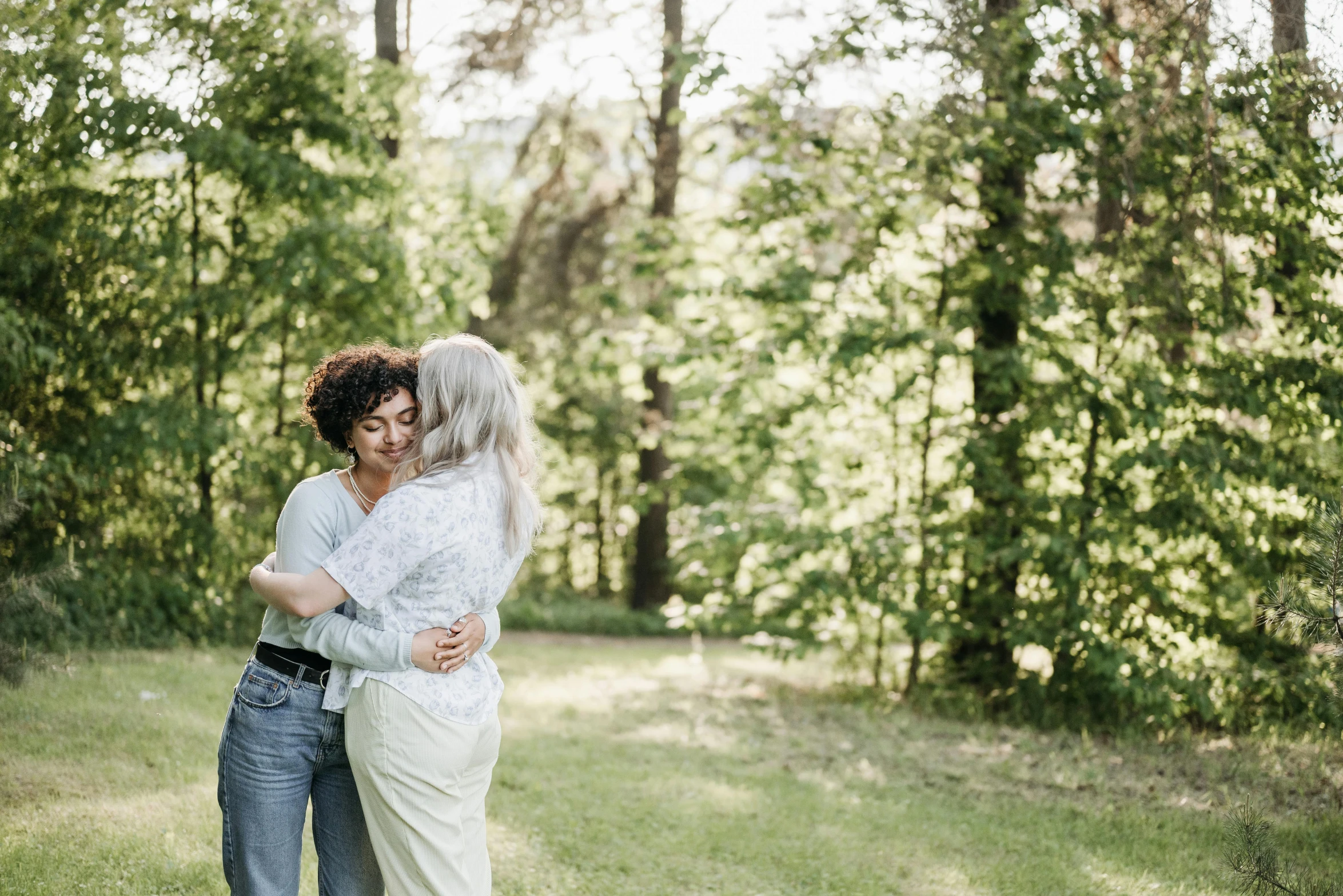 two women emcing in a grassy field in front of trees