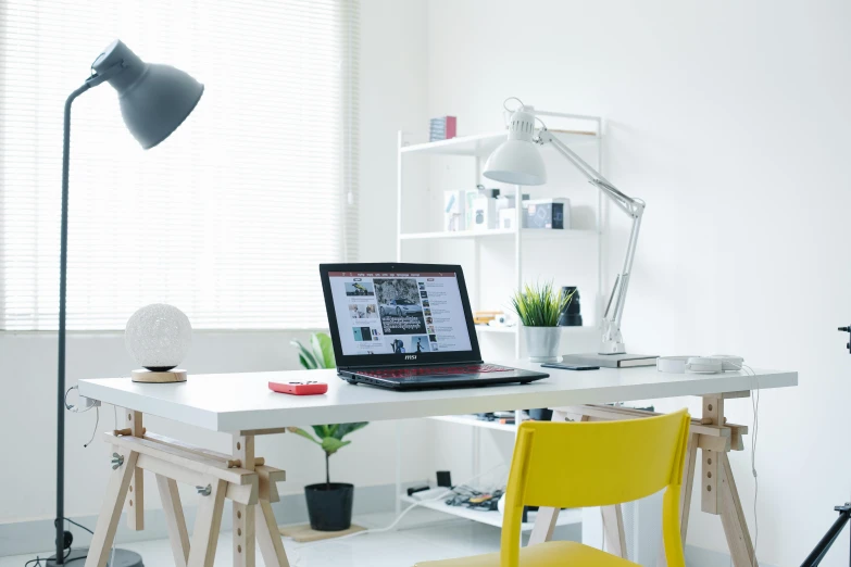 a desk with a laptop on it and a floor lamp
