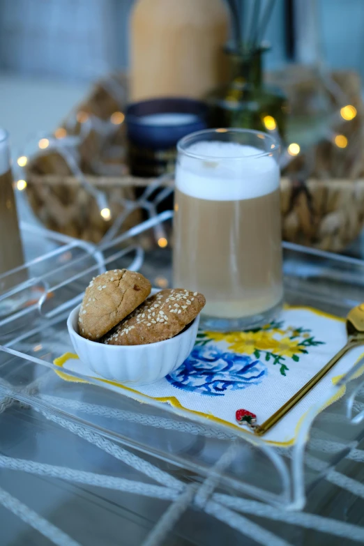 two cookies sit next to a drink on a glass tray