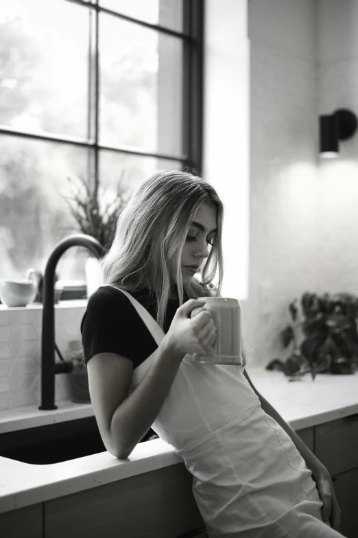 a woman sitting on top of a counter drinking out of a mug