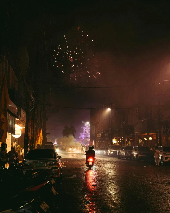 some people on bicycles on a rainy street with fireworks