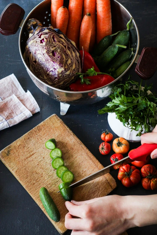 a woman is  vegetables with a knife on a board