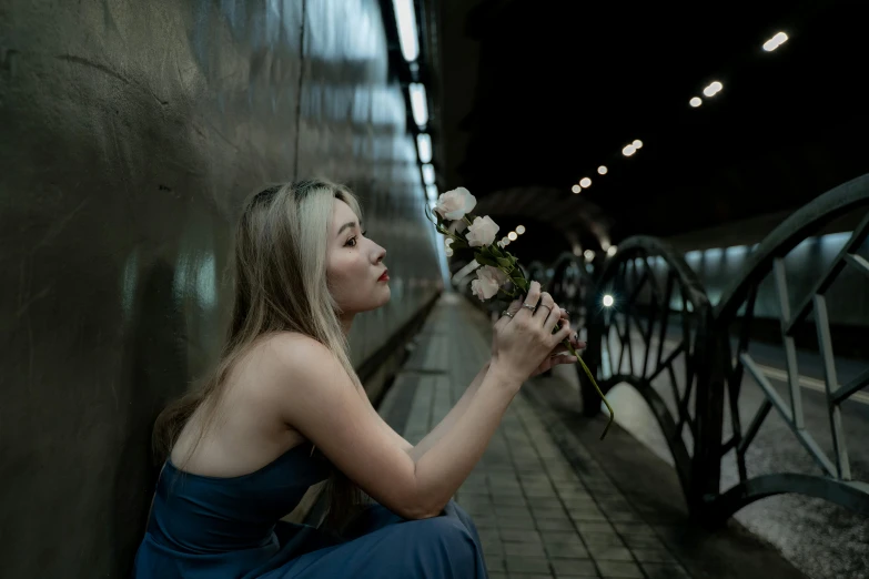 a young woman sits next to a wall