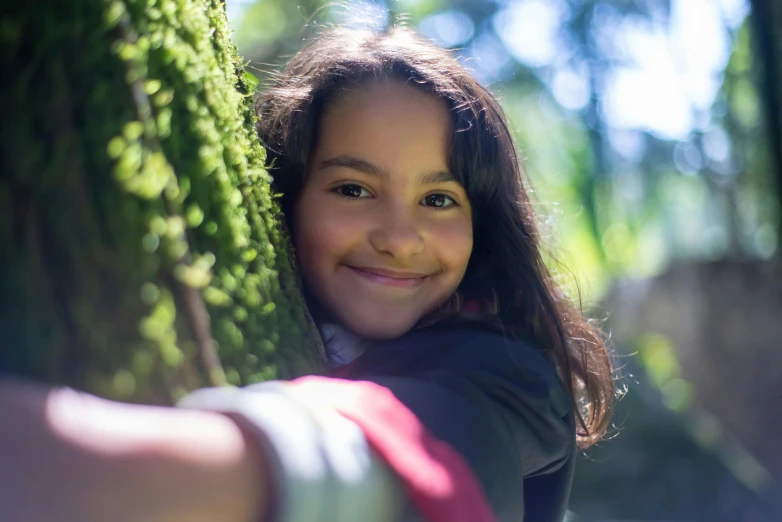 a little girl hugging a tree trunk