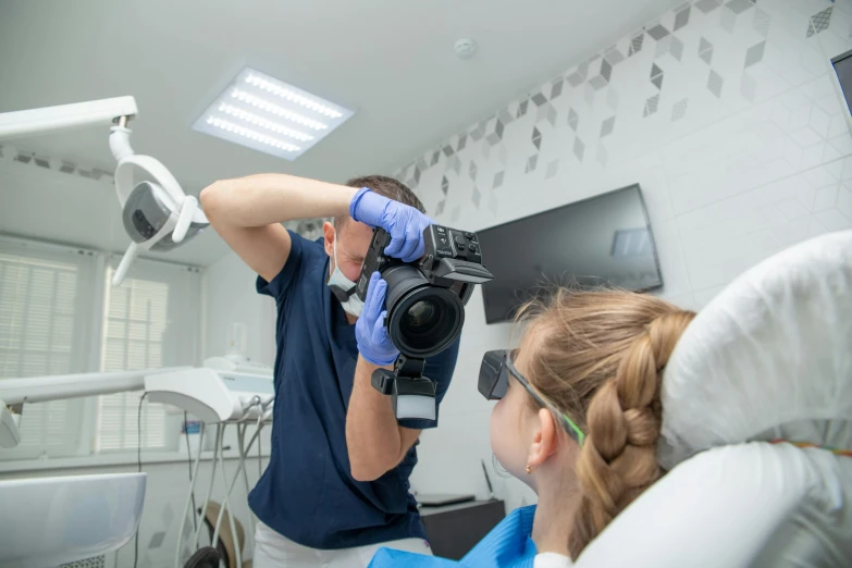 a man taking a picture of a woman on the dentist's chair