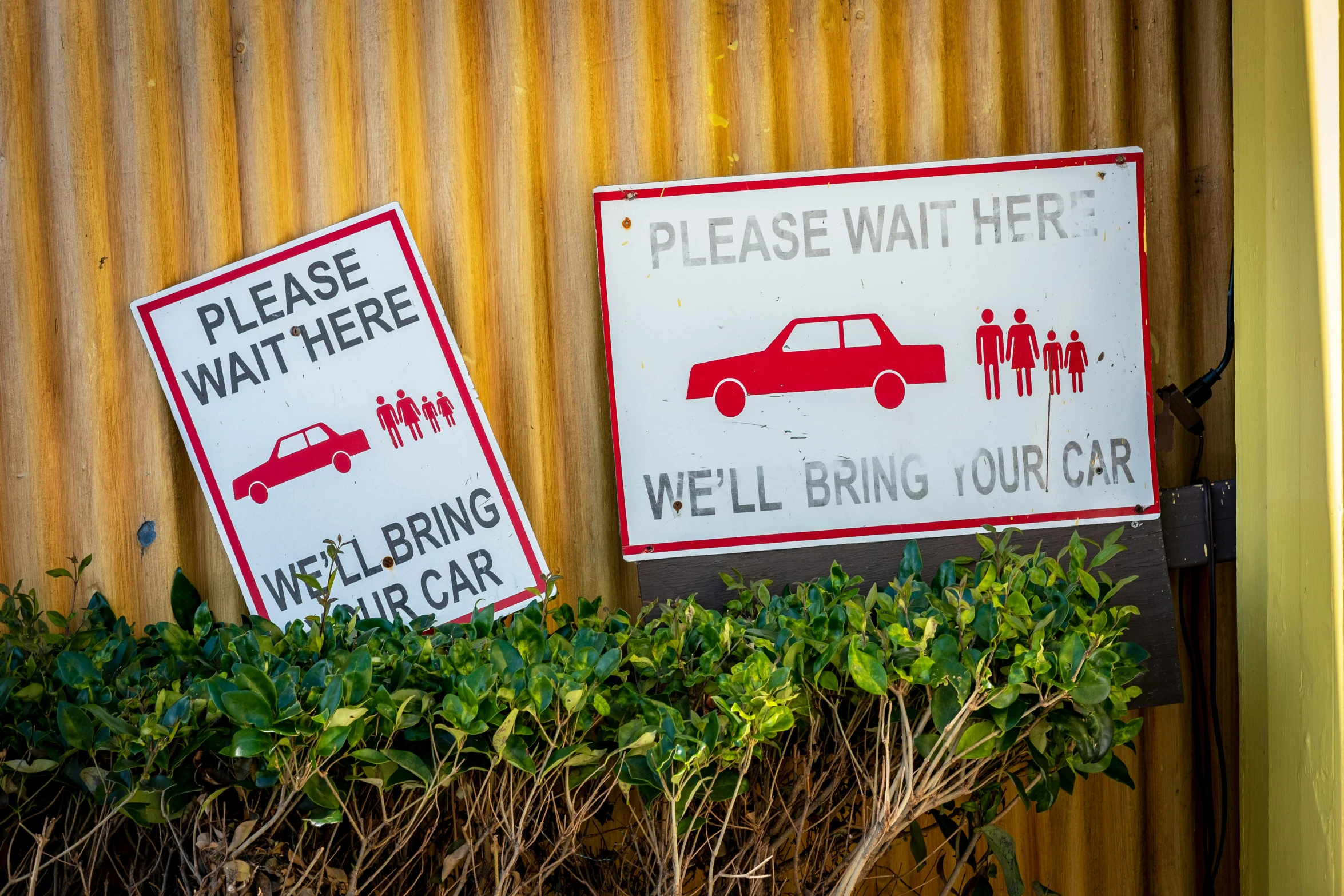 two signs posted in front of a corrugated building