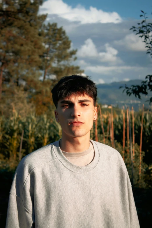 a young man standing next to a tree with no leaves on it