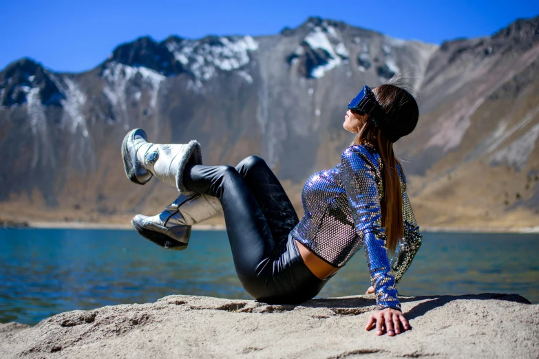 a woman is sitting on a rock near a lake