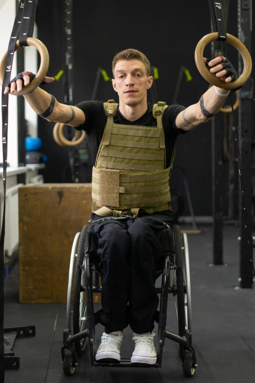 the young man is training in the gym on two wheel chairs