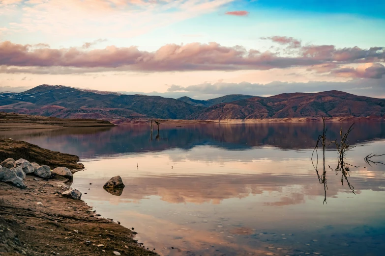 a small mountain range sits in the distance and rests on top of a lake