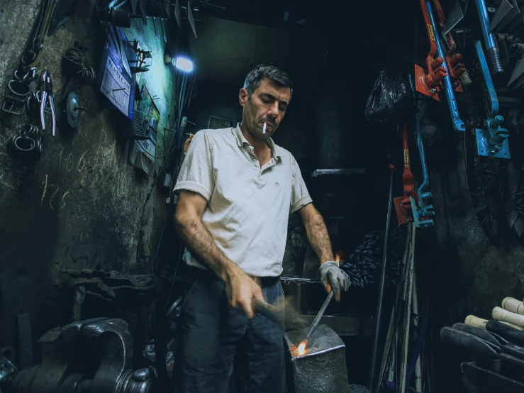 a man that is using a tong in some kind of metal