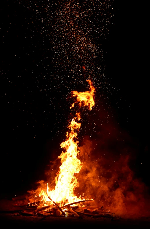 bright red flames are rising from the top of a bonfire