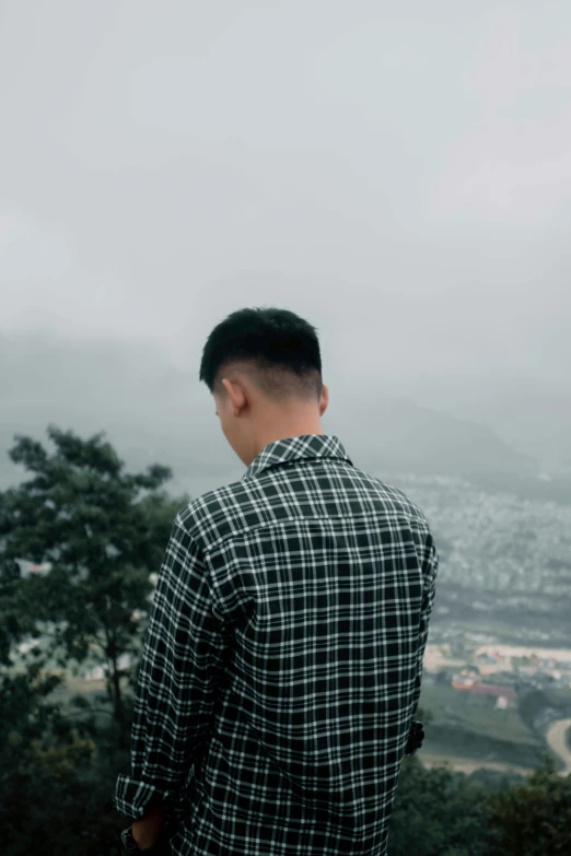 a man looking out over a city and countryside on a foggy day