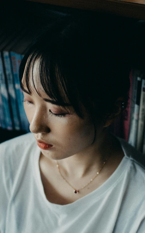 a girl in front of books with her eyes closed