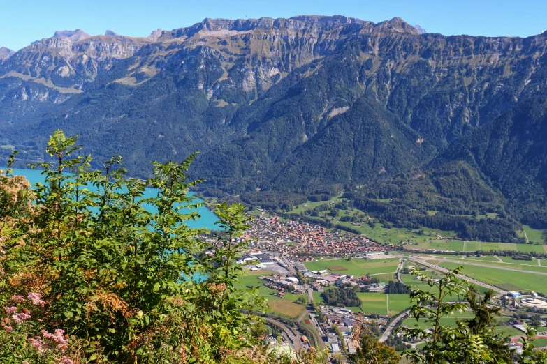 a scenic view from the top of a mountain with a green field and valley in the background