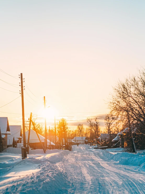 a road covered in snow at sunset with a train on it