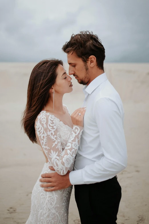 couple in white standing on beach and looking at each other