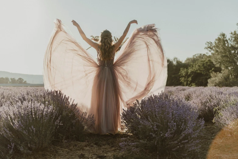 a young woman with her hands on her hips standing in the middle of lavender field